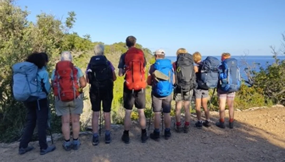 Acht Wandernde mit großen Rucksäcken stehen nebeneinander und blicken auf das Meer. | © DAV Dortmund