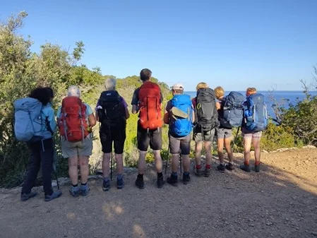 Acht Wandernde mit großen Rucksäcken stehen nebeneinander und blicken auf das Meer. | © DAV Dortmund