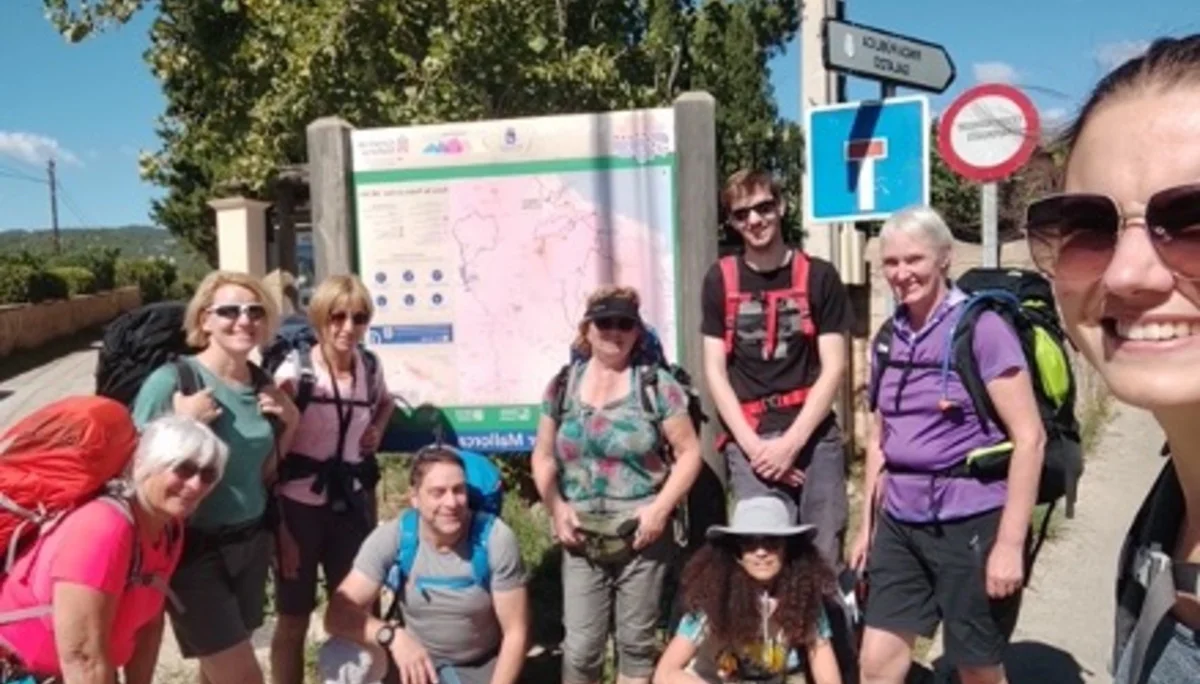 Fröhliche Wandergruppe vor einer großen Infotafel in der Sonne | © DAV Dortmund