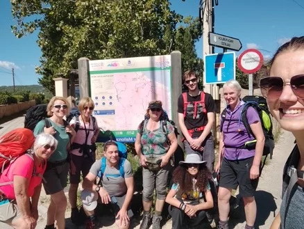 Fröhliche Wandergruppe vor einer großen Infotafel in der Sonne | © DAV Dortmund