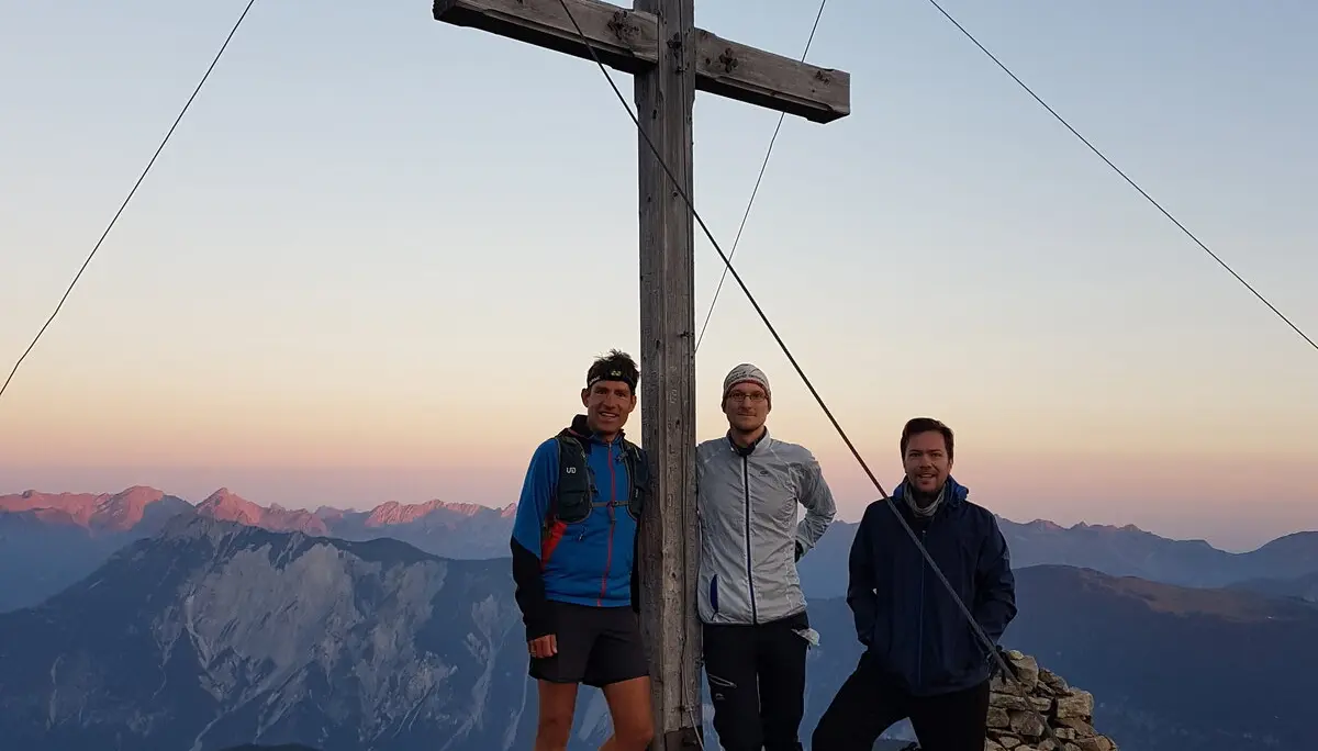 Drei Personen stehen bei Sonnenuntergang vor einem doppelten Gipfelkreuz. | © DAV Dortmund