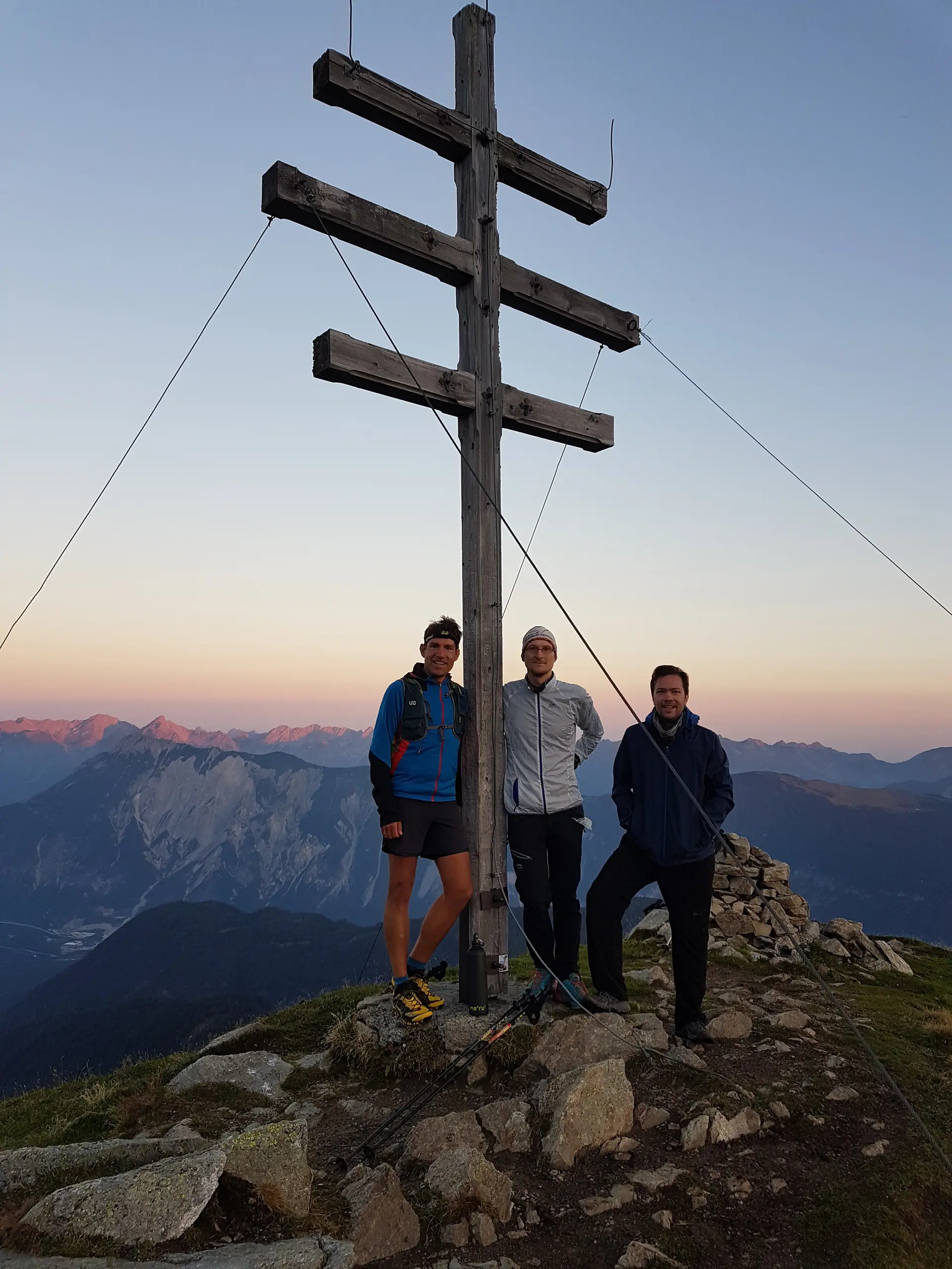 Drei Personen stehen bei Sonnenuntergang vor einem doppelten Gipfelkreuz. | © DAV Dortmund