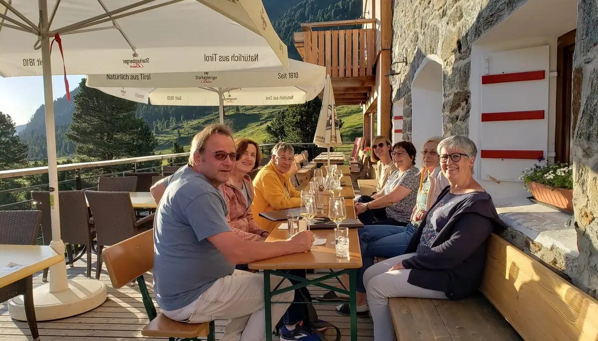 Eine Gruppe sitzt entspannt an einem Tisch auf der Terrasse der Dortmunder Hütte mit Blick auf die Berge. | © DAV Dortmund