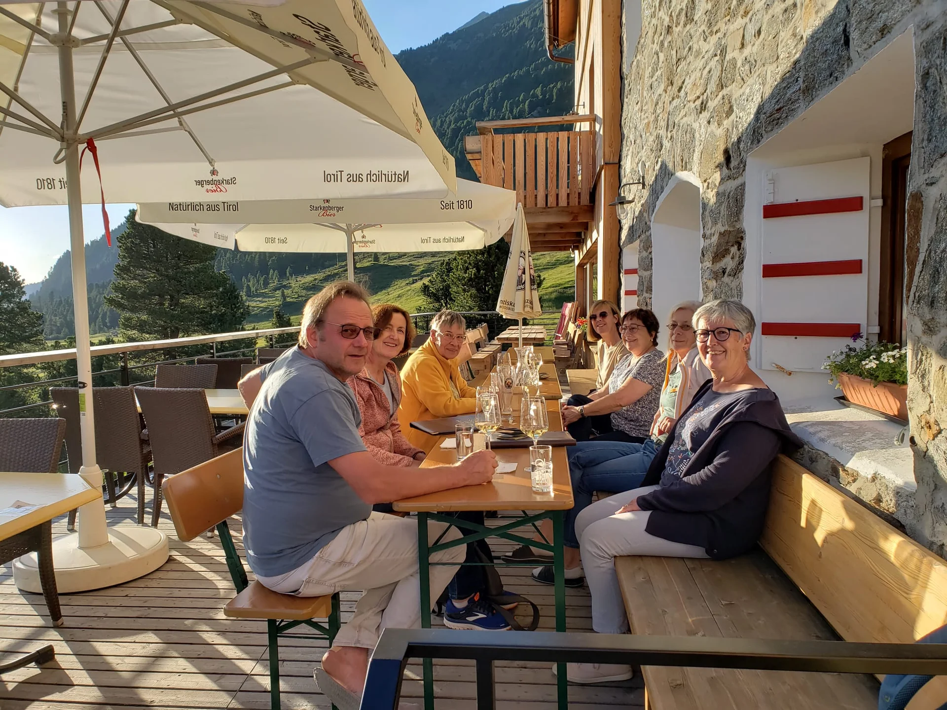 Eine Gruppe sitzt entspannt an einem Tisch auf der Terrasse der Dortmunder Hütte mit Blick auf die Berge. | © DAV Dortmund