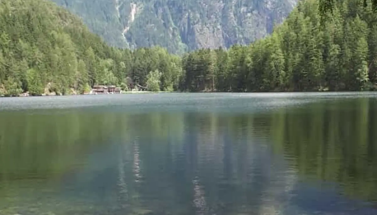 Ein ruhiger Bergsee mit Spiegelung der umliegenden Berge und Wälder, im Vordergrund ein Uferpfad. | © DAV Dortmund