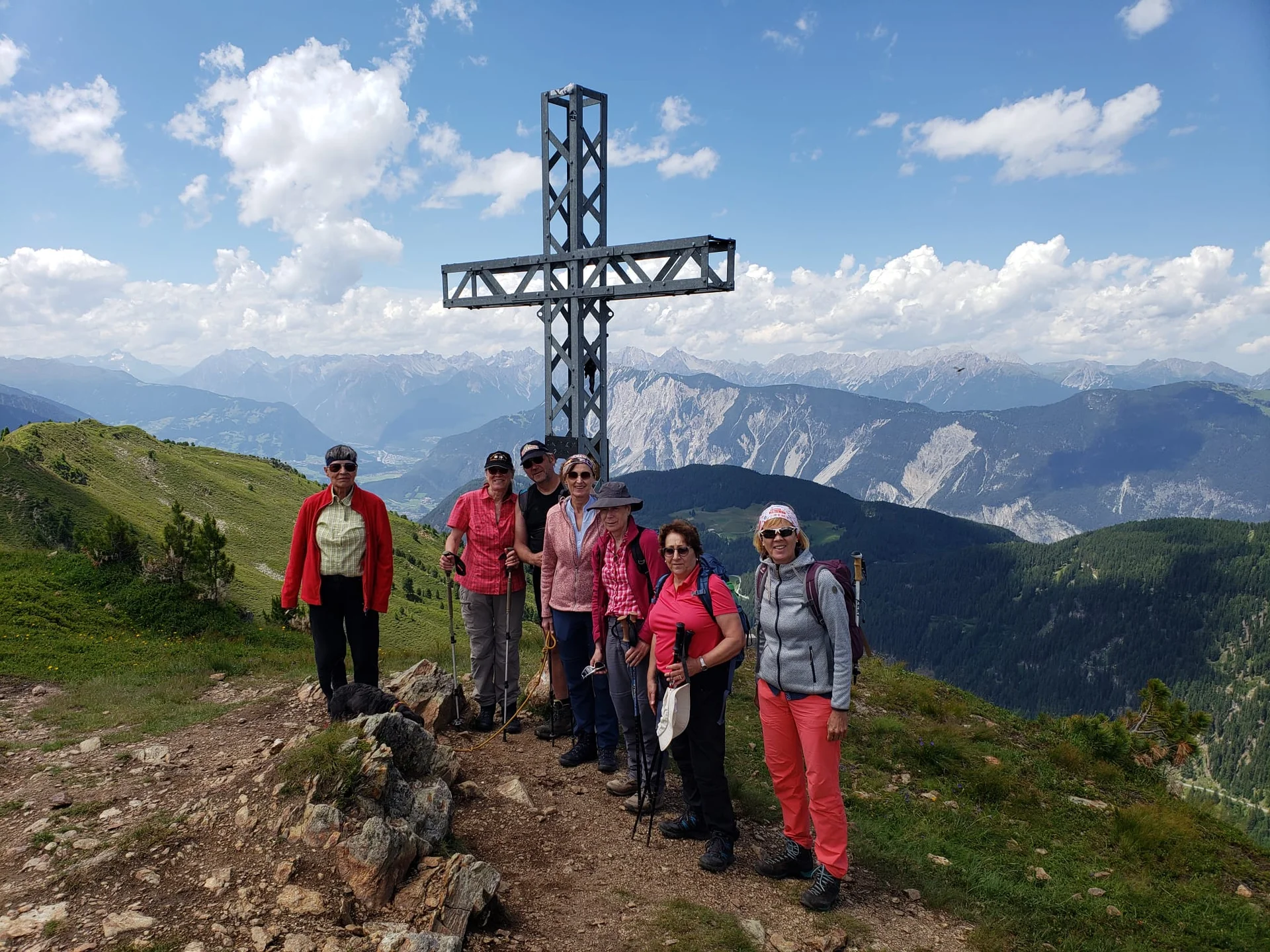 Sechs Frauen stehen am metallenen Gipfelkreuz auf einem sonnigen Berg mit Weitblick. | © DAV Dortmund