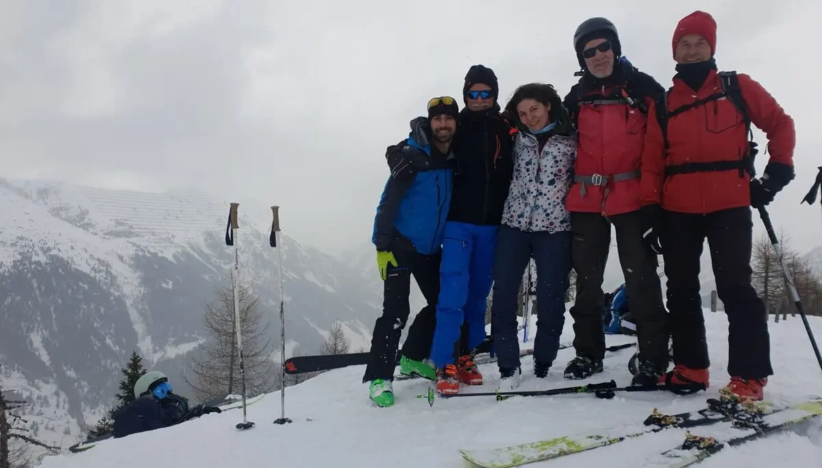Fünf Skitourengeher*innen stehen eng beieinander auf einem winterlichen Hang, Skier liegen im Schnee. | © DAV Dortmund