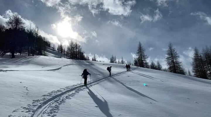 Eine Skitourengruppe zieht Spuren durch glitzernden Schnee bei tief stehender Sonne und leicht bewölktem Himmel. | © DAV Dortmund
