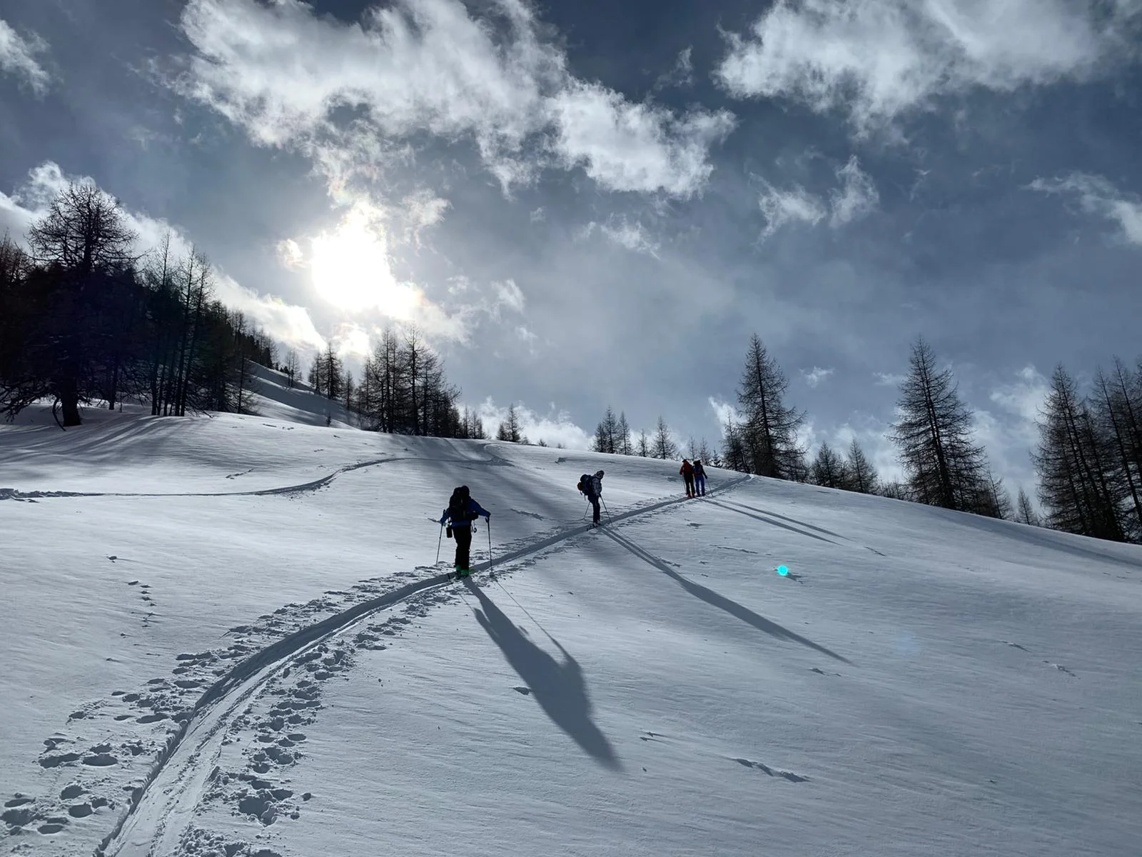 Eine Skitourengruppe zieht Spuren durch glitzernden Schnee bei tief stehender Sonne und leicht bewölktem Himmel. | © DAV Dortmund