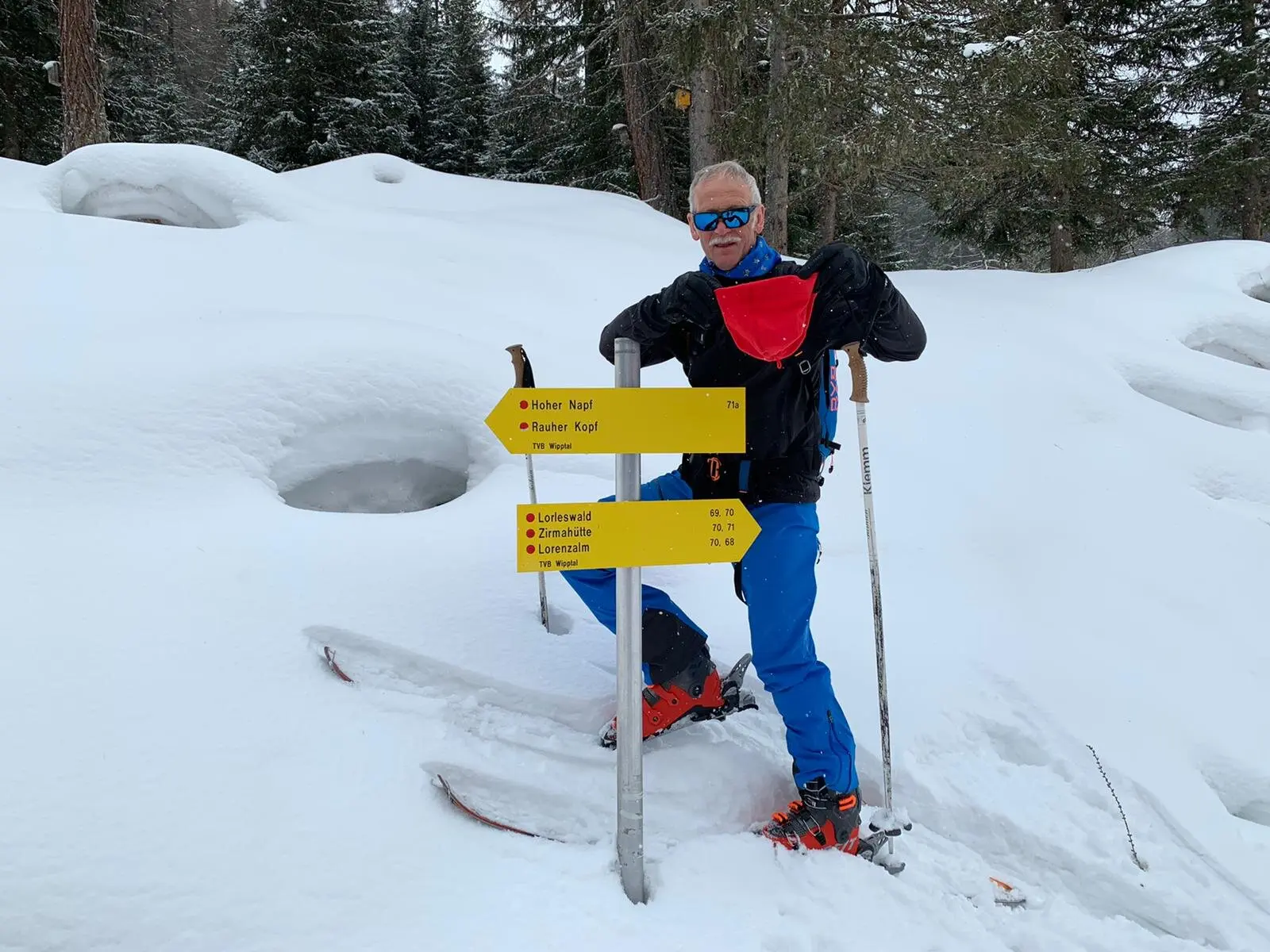 Ein Mann mit Tourenski steht an einem gelben Wegweiser im verschneiten Wald. | © DAV Dortmund