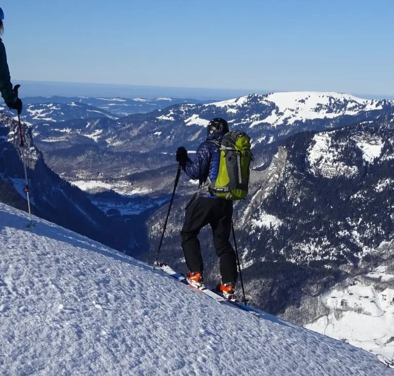 Eine Person steht mit Tourenski am Hang und blickt über ein verschneites Gebirgstal. | © DAV Dortmund