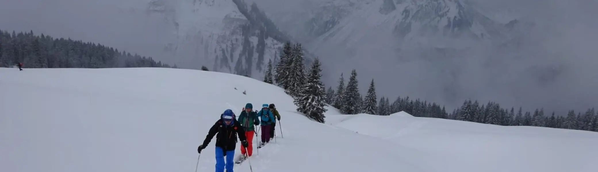 Eine Gruppe geht mit Tourenski durch tief verschneite Winterlandschaft bei bewölktem Himmel. | © DAV Dortmund