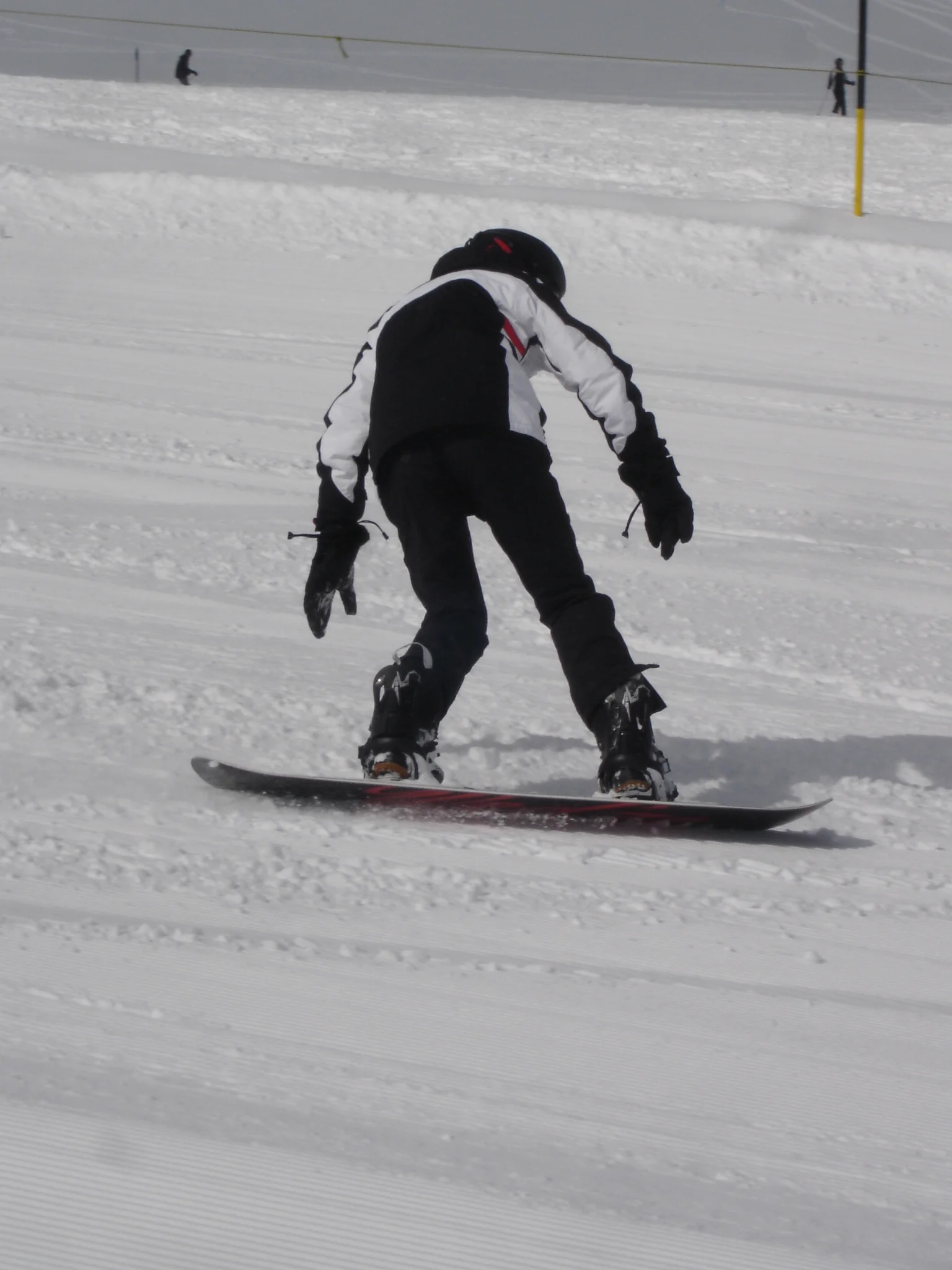 Eine Person fährt mit dem Snowboard auf einer präparierten Piste, Rückenansicht. | © DAV Dortmund