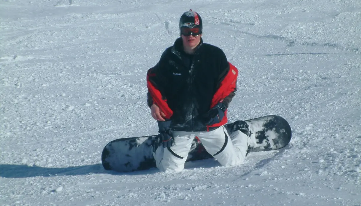 Ein Snowboarder sitzt im Schnee, das Snowboard liegt quer vor ihm, umgeben von einer verschneiten Landschaft. | © DAV Dortmund