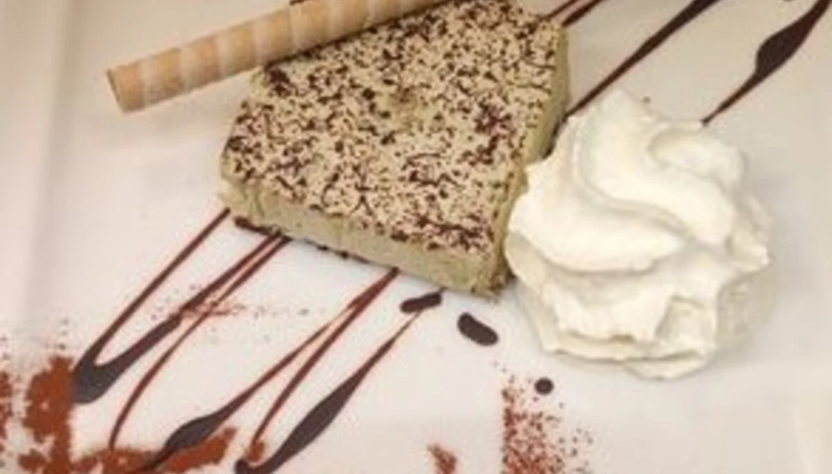 Ein dekorativ angerichtetes Dessert mit Sahne, Eiswaffel und Schokoschrift „Tirol“ auf einem Teller. | © DAV Dortmund