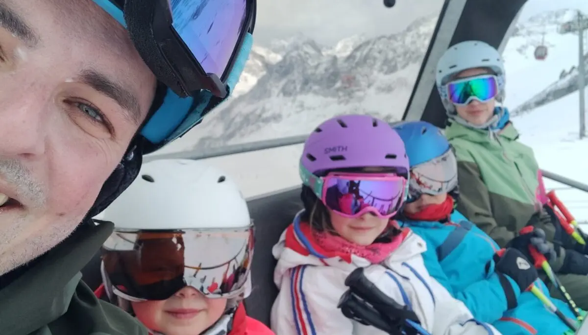 Ein Erwachsener und vier Kinder mit bunten Helmen und Skibrillen im Sessellift. | © DAV Dortmund