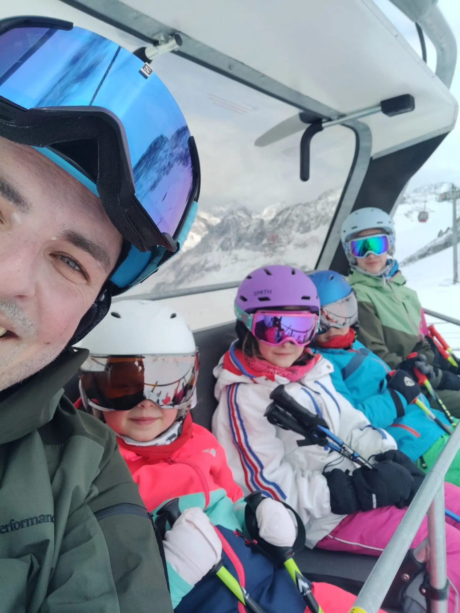 Ein Erwachsener und vier Kinder mit bunten Helmen und Skibrillen im Sessellift. | © DAV Dortmund