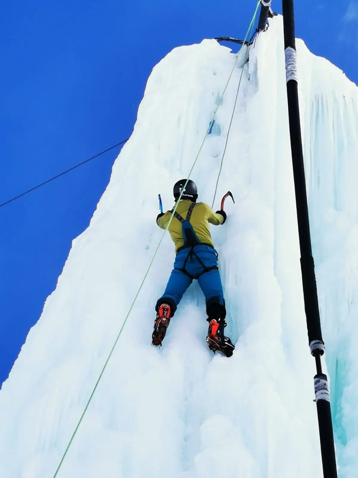 Eine Person klettert mit Steigeisen und Eisgeräten an einer senkrechten Eiswand. | © DAV Dortmund