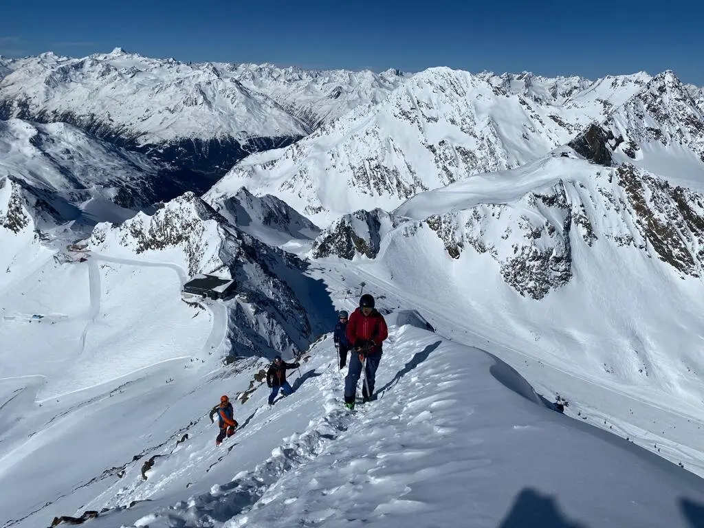 Gruppe auf Skitour steigt einen verschneiten Bergkamm mit Panorama auf die umliegenden Alpen hinauf. | © DAV Dortmund