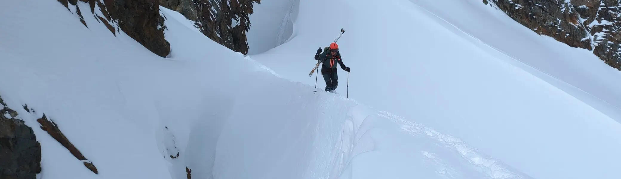 Eine Person geht auf Skitour über einen schmalen Schneekamm mit Spalten im Hochgebirge. | © DAV Dortmund