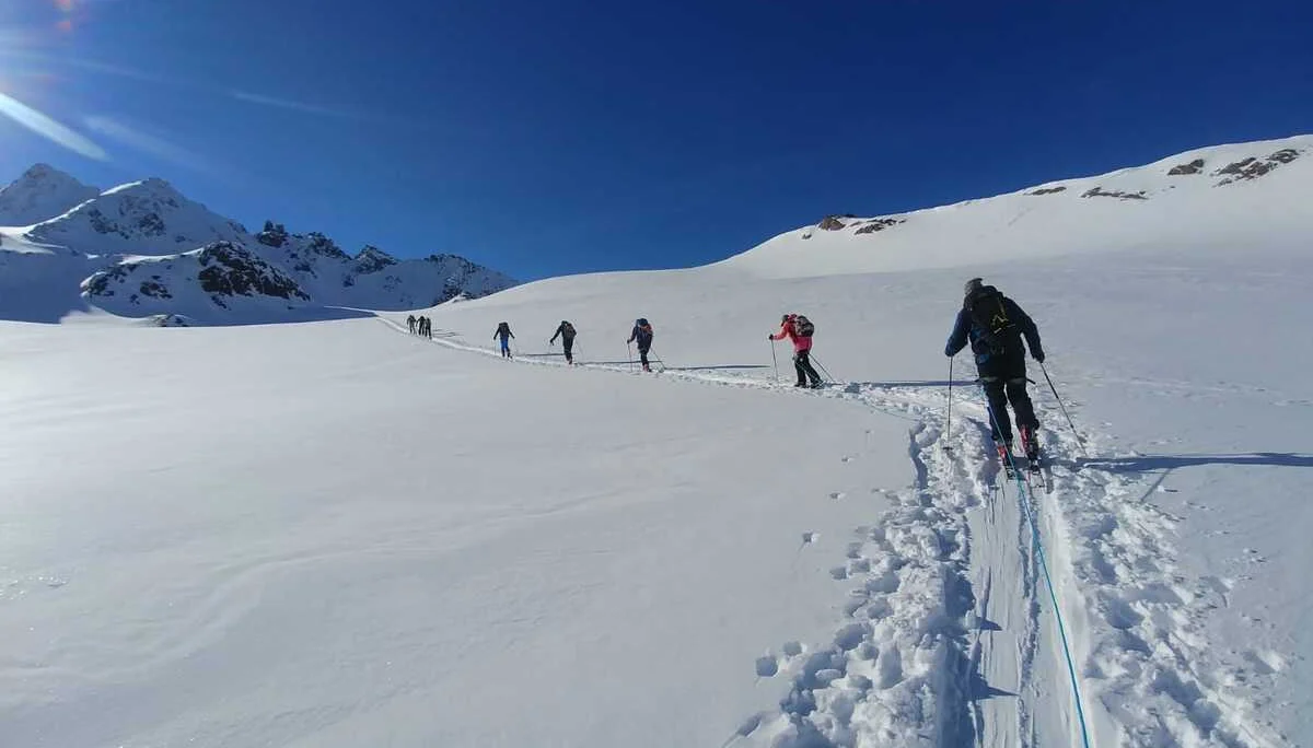 Lange Reihe von Skitourengeher*innen auf flachem, sonnigem Schneefeld. | © DAV Dortmund