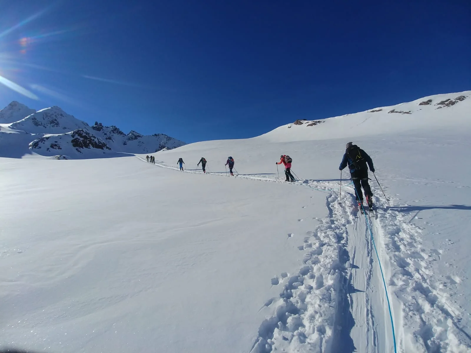 Lange Reihe von Skitourengeher*innen auf flachem, sonnigem Schneefeld. | © DAV Dortmund