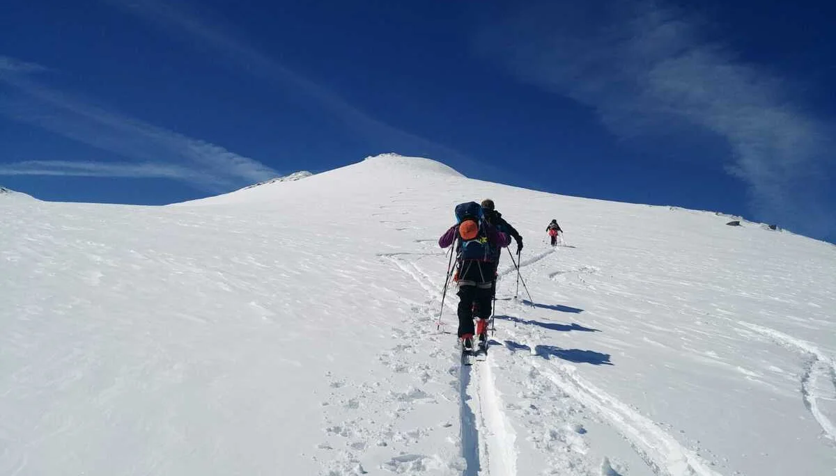 Gruppe von Skitourengeher*innen steigt bei klarem Himmel durch tiefen Schnee. | © DAV Dortmund