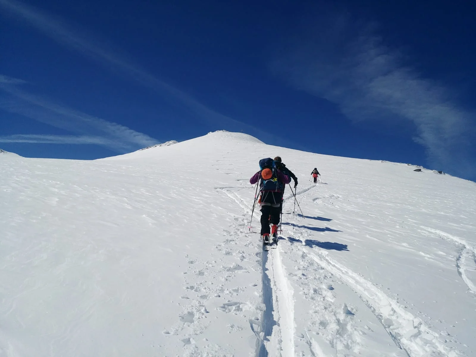 Gruppe von Skitourengeher*innen steigt bei klarem Himmel durch tiefen Schnee. | © DAV Dortmund