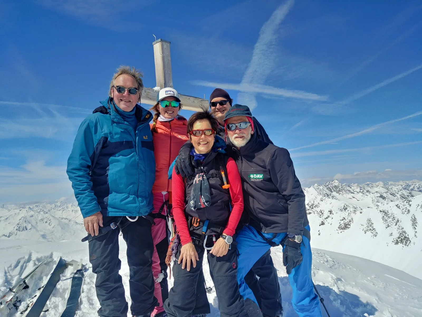 Fünf Personen stehen bei klarem Himmel vor einem Holzkreuz auf einem Gipfel inmitten der Alpen. | © DAV Dortmund