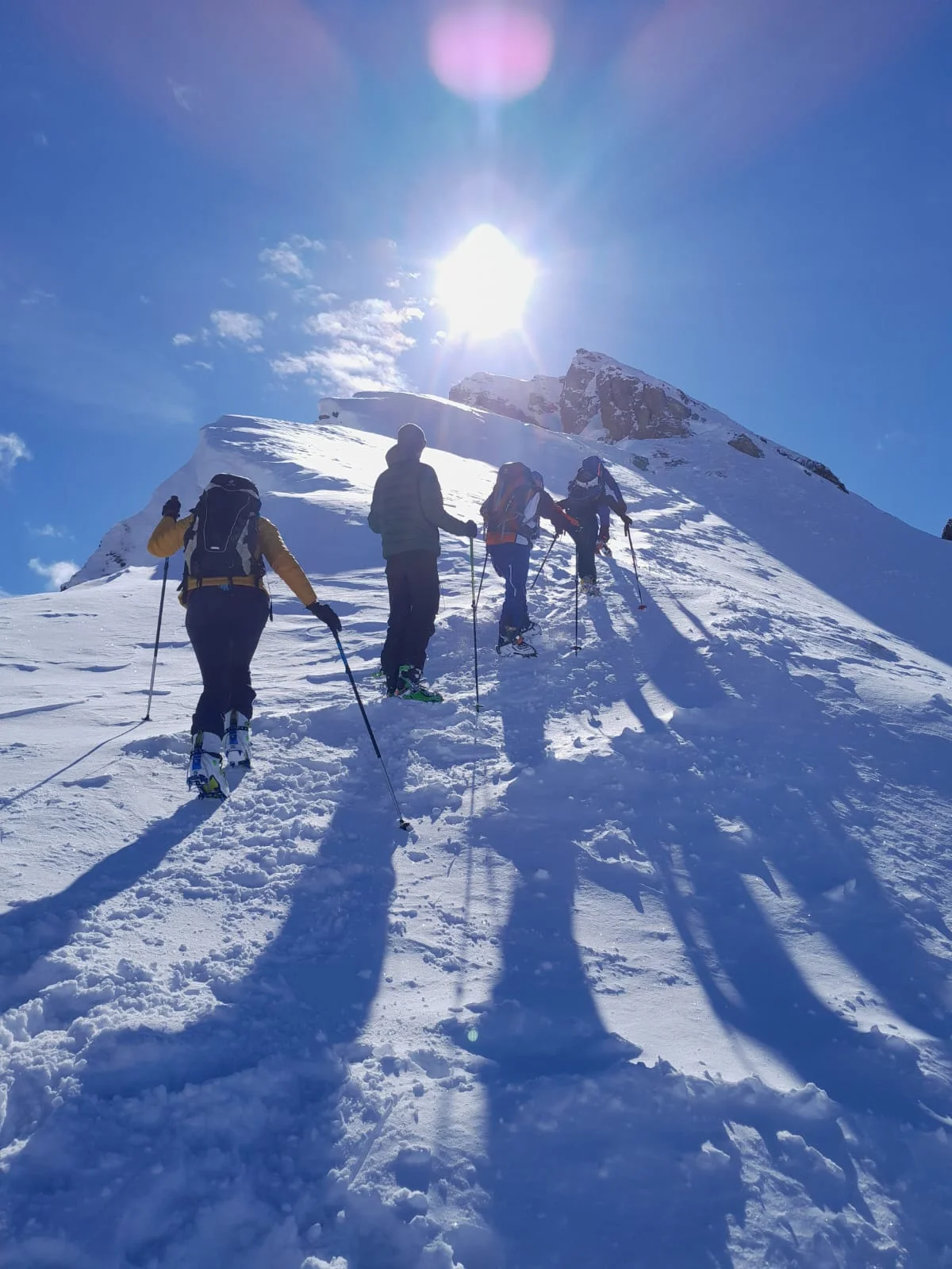 Vier Skitourengeher steigen bei Sonnenschein einen verschneiten Grat hinauf. | © DAV Dortmund