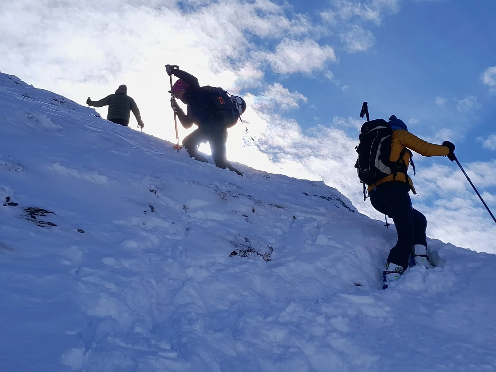 Drei Skitourengeher steigen bei tief stehender Sonne einen verschneiten Hang hinauf. | © DAV Dortmund