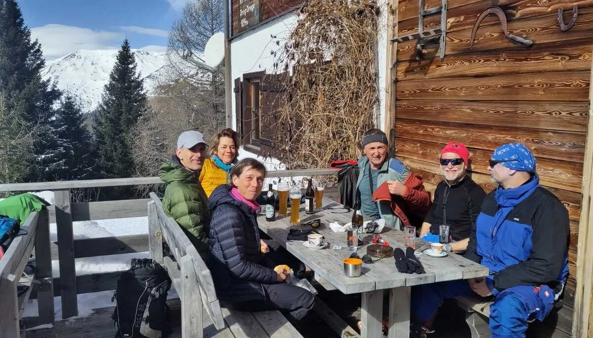 Gruppe von Personen sitzt vor einer Berghütte und genießt warme Getränke. | © DAV Dortmund