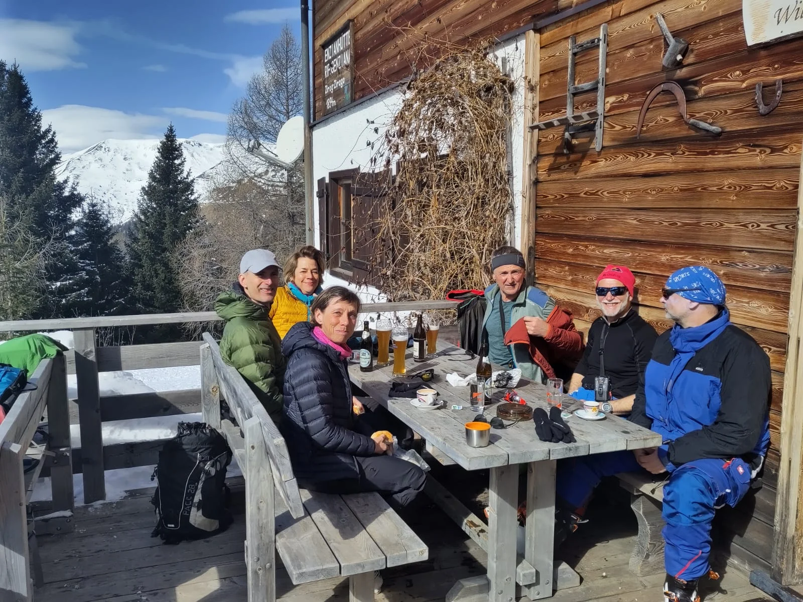 Gruppe von Personen sitzt vor einer Berghütte und genießt warme Getränke. | © DAV Dortmund