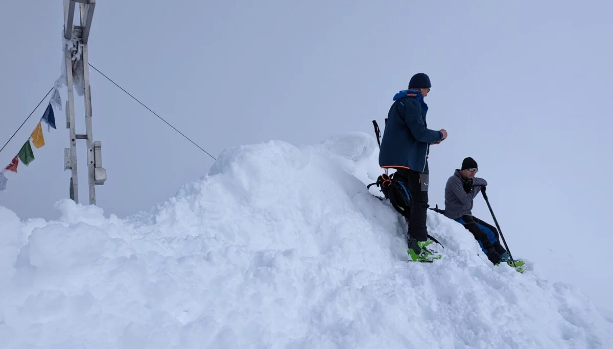  Zwei Personen stehen mit Skiern auf einem schneebedeckten Gipfel neben einem Kreuz mit Gebetsfahnen. | © DAV Dortmund