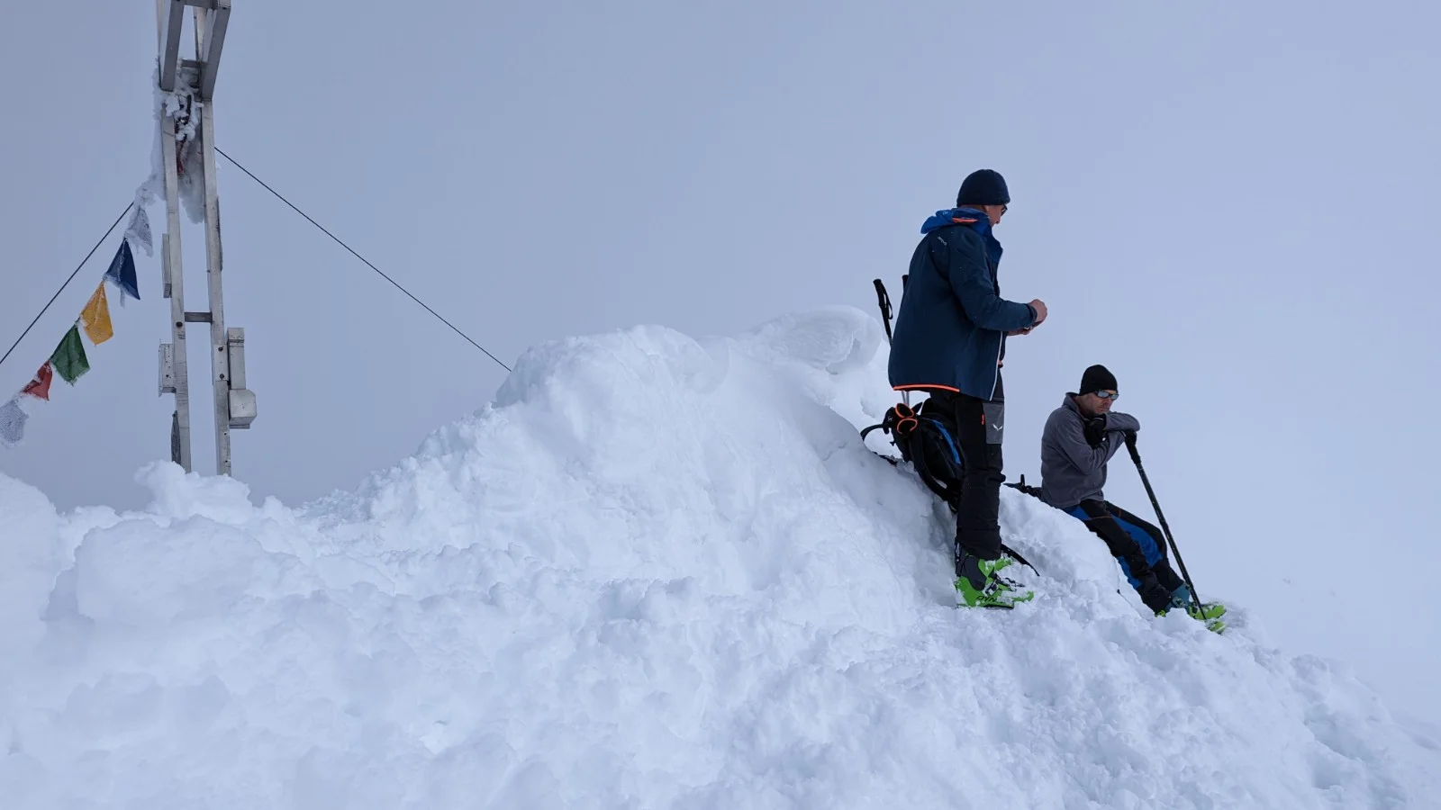  Zwei Personen stehen mit Skiern auf einem schneebedeckten Gipfel neben einem Kreuz mit Gebetsfahnen. | © DAV Dortmund