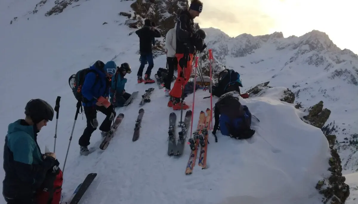 Gruppe bereitet sich auf Skitour vor und befestigt die Ski am Rucksack in alpinem Gelände. | © DAV Dortmund
