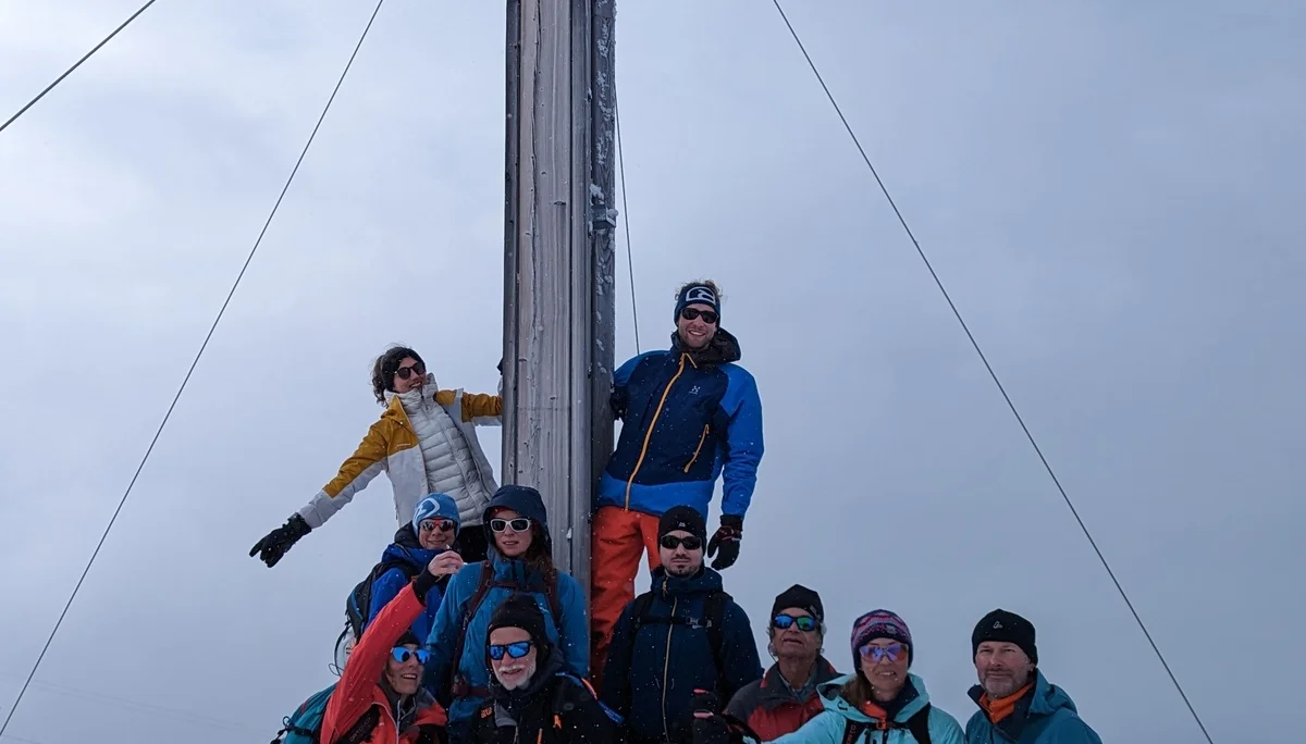 Gruppe posiert an einem Gipfelkreuz bei nebligem Winterwetter. | © DAV Dortmund