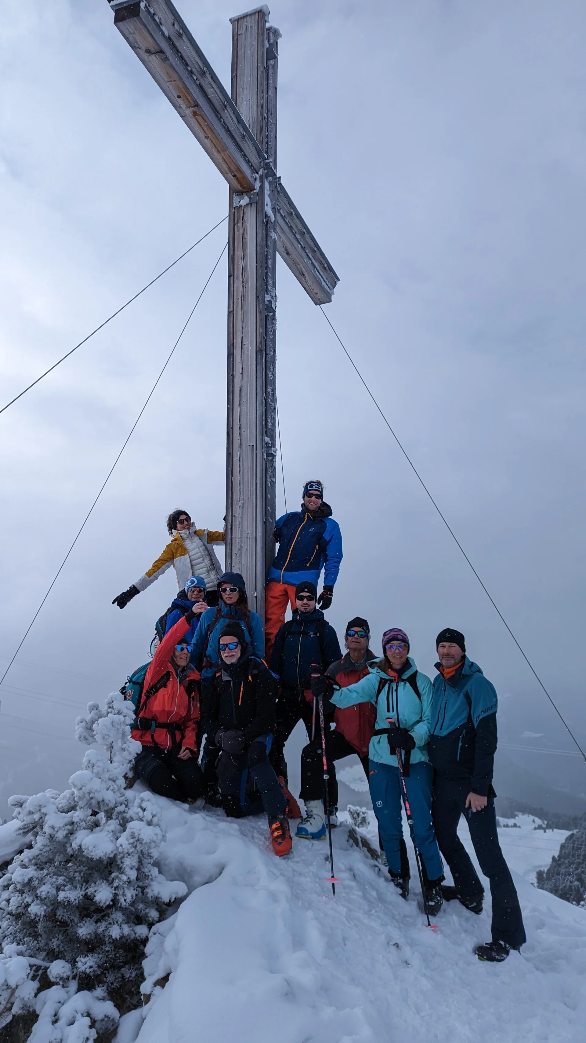 Gruppe posiert an einem Gipfelkreuz bei nebligem Winterwetter. | © DAV Dortmund