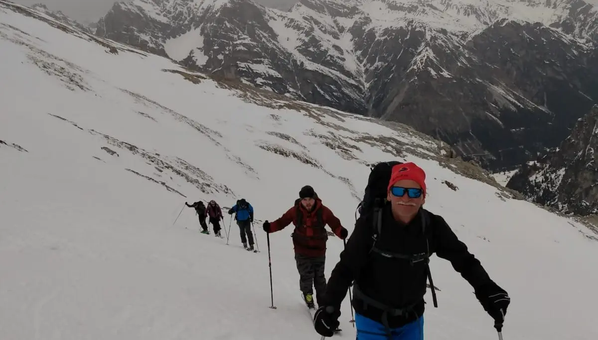 Eine Skitourengruppe steigt über einen breiten Hang mit Ausblick auf verschneite Berggipfel. | © DAV Dortmund