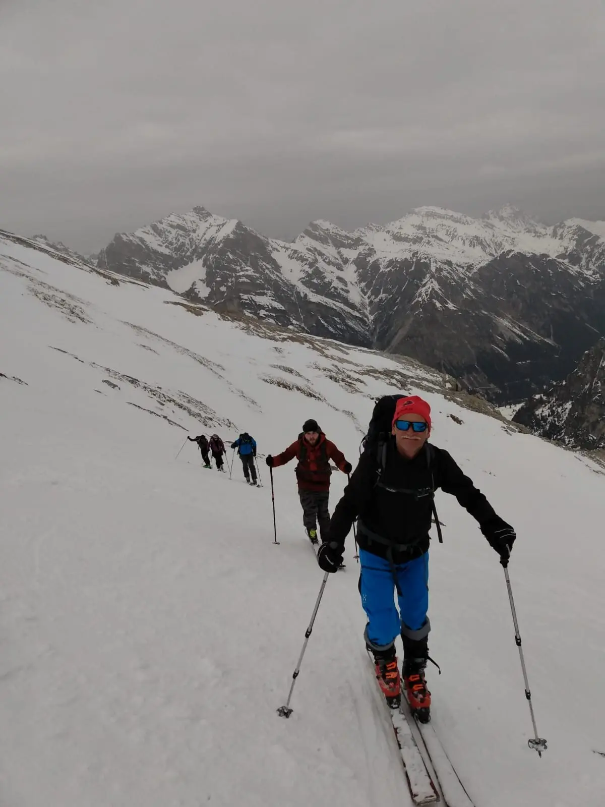 Eine Skitourengruppe steigt über einen breiten Hang mit Ausblick auf verschneite Berggipfel. | © DAV Dortmund