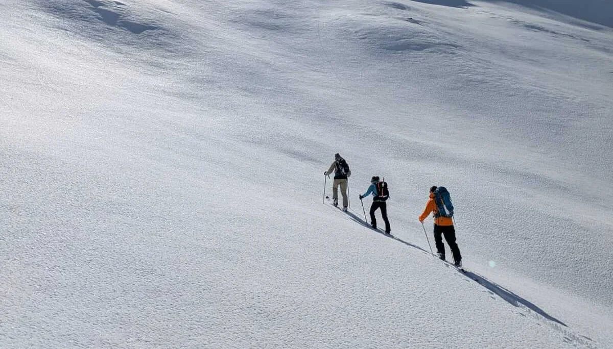 Drei Skitourengeher*innen steigen im Morgenlicht über eine weiße Schneefläche auf. | © DAV Dortmund