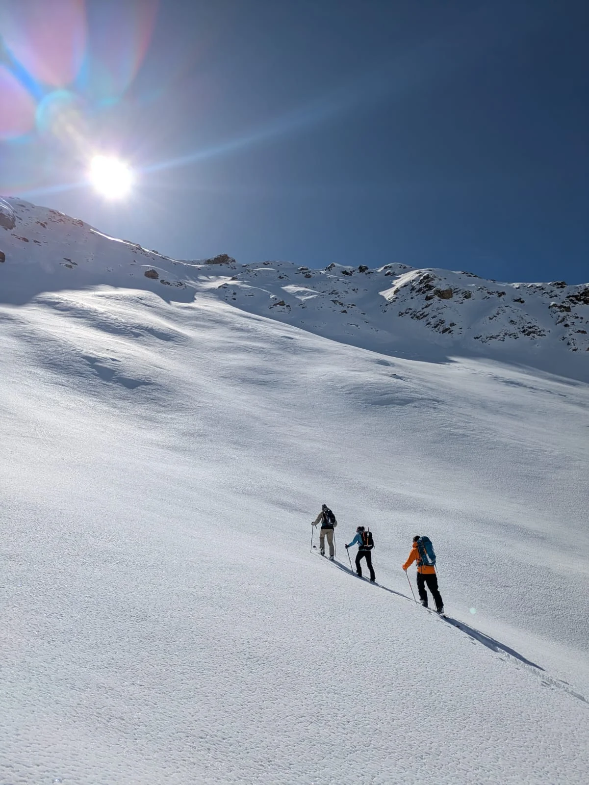 Drei Skitourengeher*innen steigen im Morgenlicht über eine weiße Schneefläche auf. | © DAV Dortmund