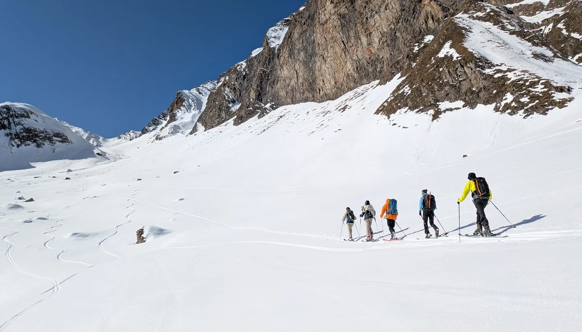 Sechs Skitourengeher*innen gehen durch weite Schneelandschaft unter Felswänden. | © DAV Dortmund