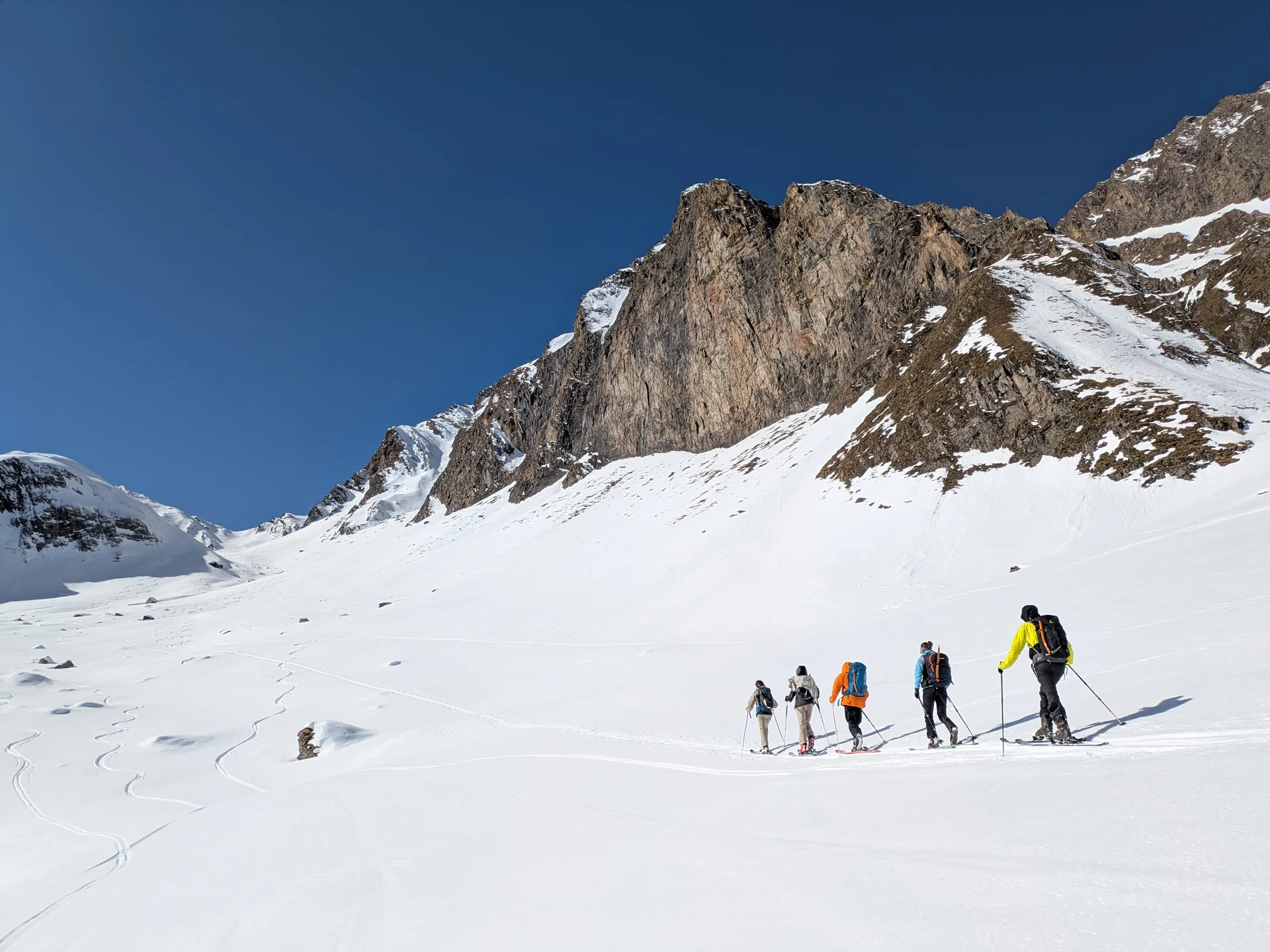 Sechs Skitourengeher*innen gehen durch weite Schneelandschaft unter Felswänden. | © DAV Dortmund