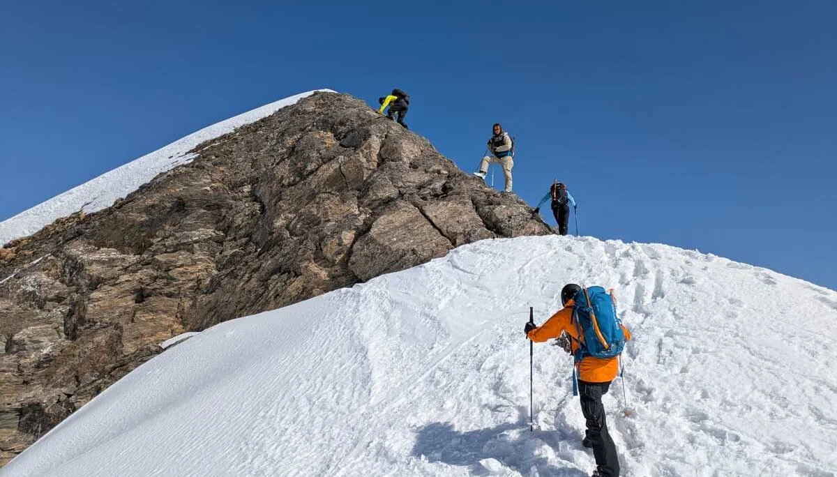 Vier Personen steigen über einen verschneiten Bergkamm auf einen felsigen Gipfel zu. | © DAV Dortmund
