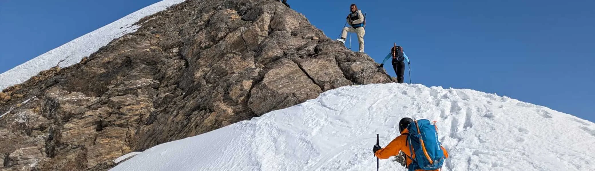 Vier Personen steigen über einen verschneiten Bergkamm auf einen felsigen Gipfel zu. | © DAV Dortmund