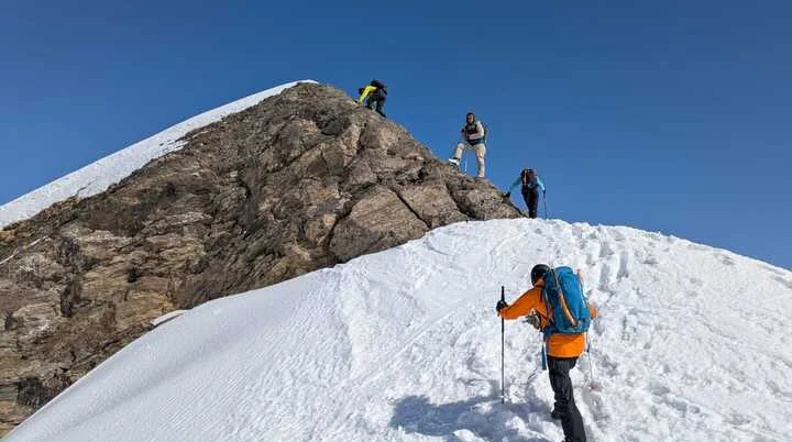 Vier Personen steigen über einen verschneiten Bergkamm auf einen felsigen Gipfel zu. | © DAV Dortmund