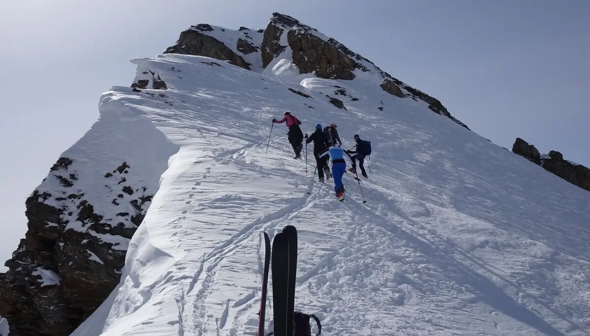 Eine Gruppe steigt auf einem schmalen, verschneiten Grat mit Tourenski Richtung Gipfel. | © DAV Dortmund
