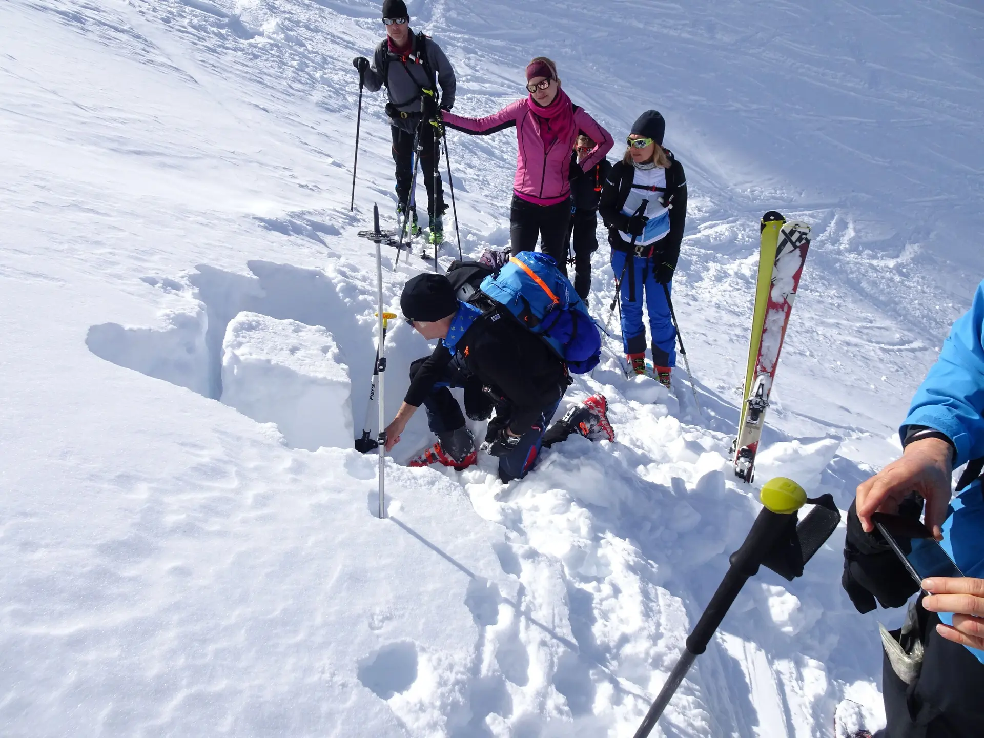 Eine Gruppe beobachtet eine Person, die ein Schneeprofil im Tiefschnee für eine Lawinenbeurteilung gräbt. | © DAV Dortmund