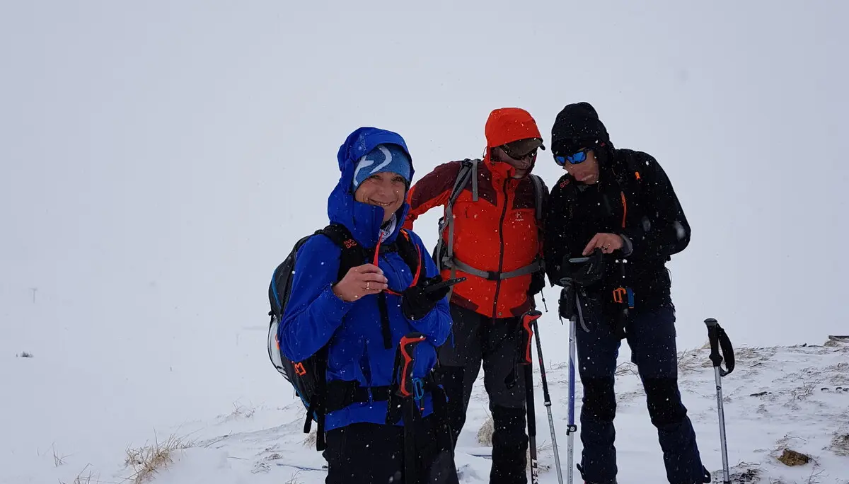 Drei Skitourende prüfen bei Schneetreiben ihre Ausrüstung und Route. | © DAV Dortmund